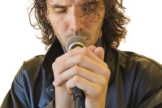 Portrait of a young man in a leather jacket singing in a romantic way in a microphone. Front shot