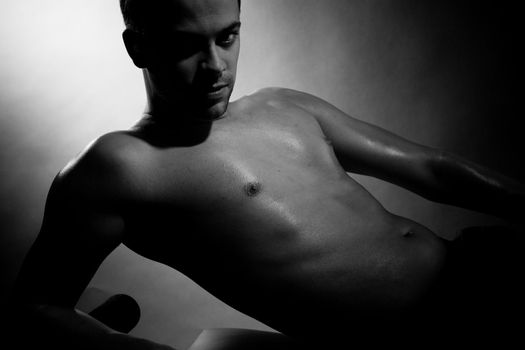 Half naked man lying with his chest bare on dark background