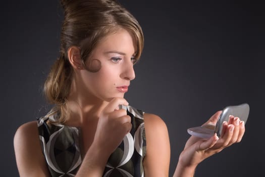 Beautiful blond woman in fifties outfit checking her makeup