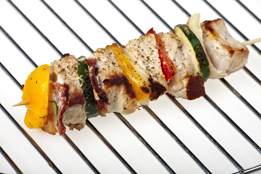 grilled shashlik on a charcoal grate over a white background