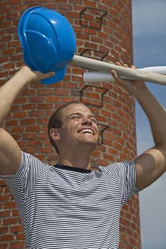 smiling young architect holding a hard hat and blueprints