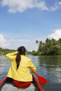 Woman in yellow jacket paddling red canoe