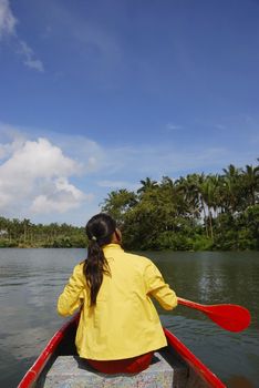 Woman in yellow jacket paddling red canoe