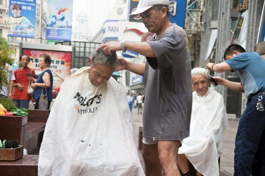 Chinese elders having their hair cut along Nanjing Road, Shanghai