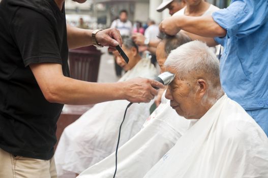 Chinese elders having their hair cut along Nanjing Road, Shanghai