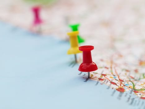 Series of colored pin pointing locations on a french map with selective focus on the red pin