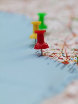 Series of colored pin pointing locations on a french map with selective focus on the red pin