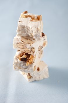 Delicious pieces of nougat stacked together on light blue background