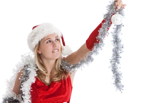 Cute young girl in santa outfit trying to reach up to hang the baubles in the tree