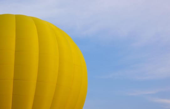 Part of a yellow hot air balloon against a blue sky