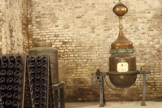 Bottles of wine aging in an old cellar with an ancient machine