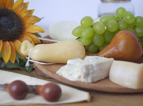 Table with several kind of cheese, pear, grape