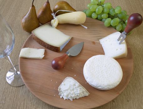 Table with several kind of cheese, pear, grape