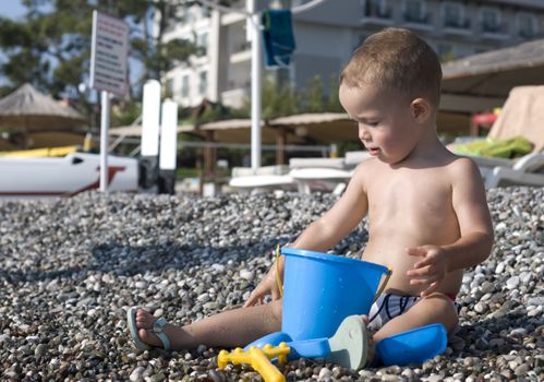 One and half year old child sitting on the pebble beach