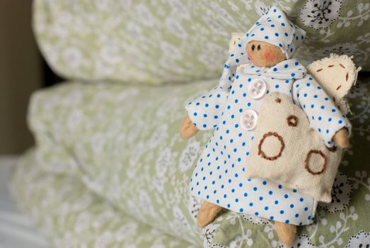 Handmade rag-doll with pillow in hand on pile of pillows