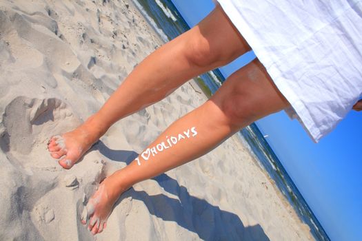 Woman with creamy sign I love holidays on her legs
