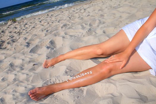 Woman with creamy sign I love holidays on her legs
