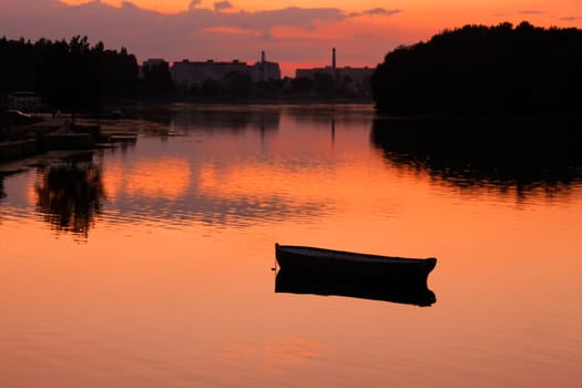 View anchored boat in the reservoir after sunset in quiet summer weather. Khmelnitsky, 