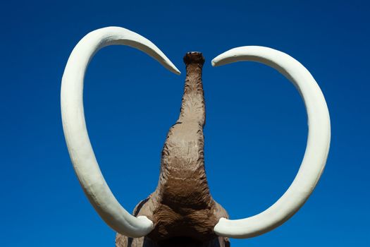 Sculpture of extinct woolly mammoth with impressive tusks and trunk.