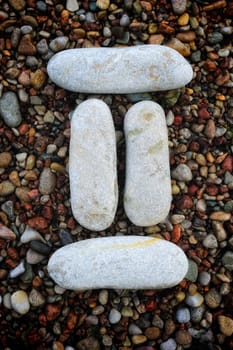 Number "2" form of pebbles, isolated on the background of sea gravel