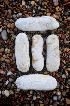 Number "3" form of pebbles, isolated on the background of sea gravel