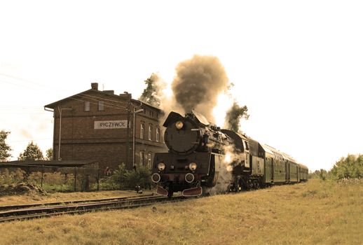 Old retro steam train starting from the small station
