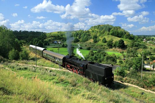 Beautiful hilly landscape with an old retro steam train
