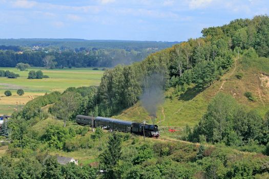 Beautiful hilly landscape with an old retro steam train
