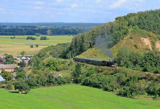 Beautiful hilly landscape with an old retro steam train
