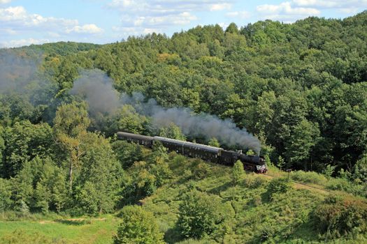 Beautiful hilly landscape with an old retro steam train
