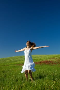 Beautiful happy young woman dancing on the field 