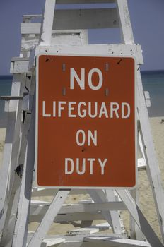 Empty lifeguard tower chair with not on duty sign