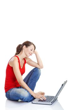 Beautiful and happy young woman sitting on floor and working on a laptop