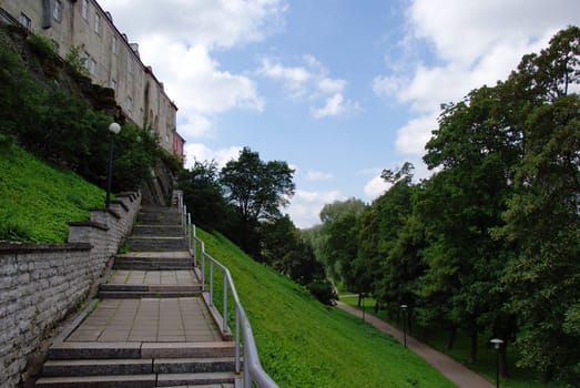 Long stairs on a green slope on a background of the sky