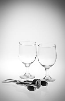 A black and white of empty glasses and a corkscrew.