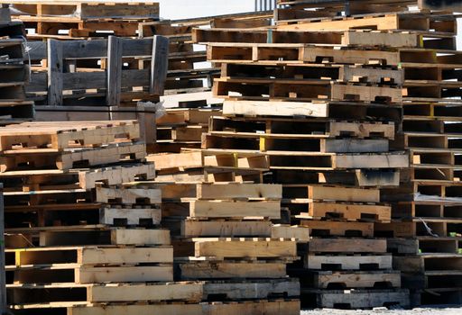 Piles of stacked wood pallets outside of warehouse.