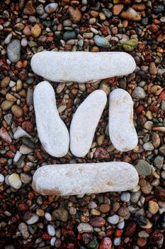 Number "6" form of pebbles, isolated on the background of sea gravel