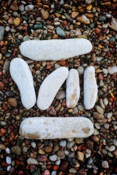 Number "7" form of pebbles, isolated on the background of sea gravel