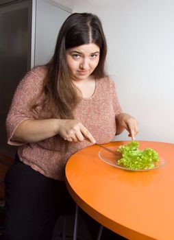 Stout woman trying to eat a leaf of lettuce