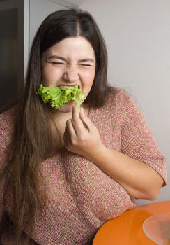Stout woman trying to eat a leaf of lettuce