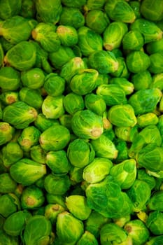 A pile of bright green brussell sprouts in various shapes and sizes