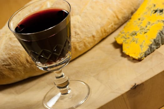 A glass of french red wine with fresh bread and cheese