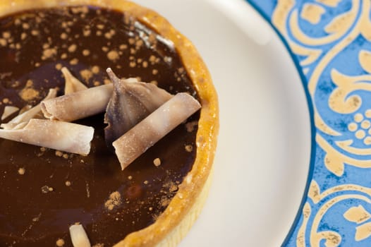 A close up of a rich chocolate tart on a blue and white plate