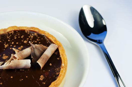 A sweet dark chocolate tart with a silver spoon