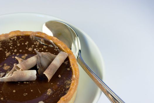 A delicious rich chocolate tart and a silver spoon 