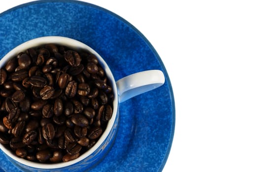 A cup and saucer filled with dark roasted coffee beans