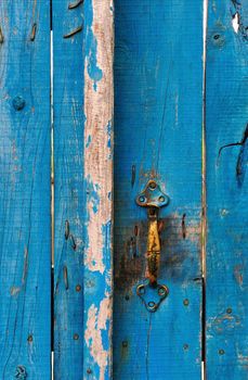 highly textured blue wooden gate with a bronze handle