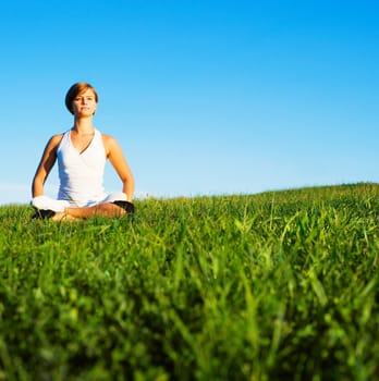 Young woman doing yoga in a sunny meadow, from a complete series of photos.