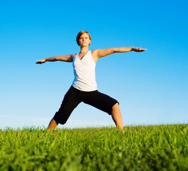 Young woman doing yoga in a sunny meadow, from a complete series of photos.