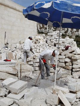 Goreme, Cappadocia, Turkey - June, 2011: Men at work, Turkish builders protected from hot sun by shade of parasol